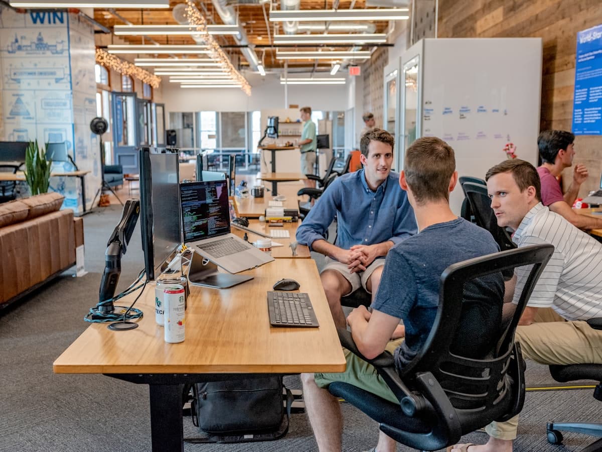 Colleagues having a conversation at a desk in an open office