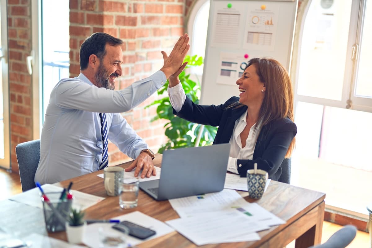 Two small business owners celebrating a win at their desk